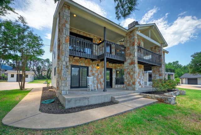 13111 Mansfield Dr, Austin, TX 78732 - back of property featuring a balcony, stone siding, a yard, and covered porch