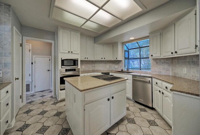 13111 Mansfield Dr, Austin, TX 78732 - kitchen featuring appliances with stainless steel finishes, white cabinets, a kitchen island, and tasteful backsplash
