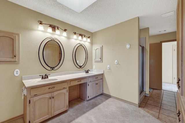 642 Lakebreeze Dr, Canyon Lake, TX 78133 - bathroom featuring double vanity, a textured ceiling, a skylight, and a shower with door