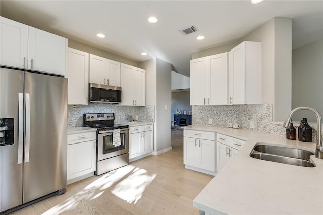 4105 Canyon Glen Cir, Austin, TX 78732 - kitchen with stainless steel appliances, decorative backsplash, white cabinets, recessed lighting, and light countertops