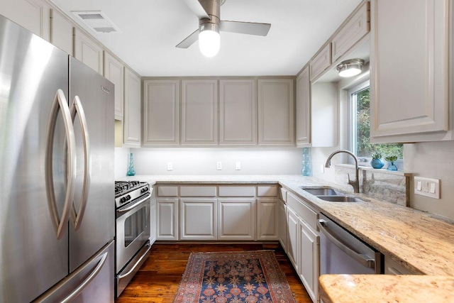 2606 Rockingham Dr, Austin, TX 78704 - kitchen featuring appliances with stainless steel finishes, ceiling fan, light stone counters, dark wood-style floors, and gray cabinets