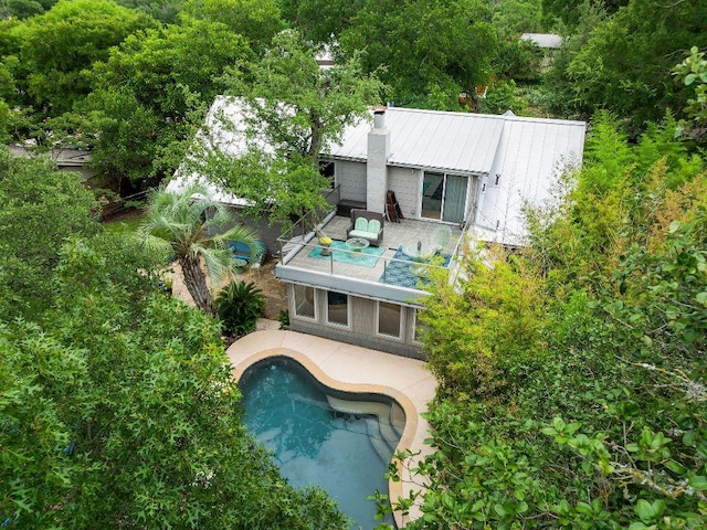 2606 Rockingham Dr, Austin, TX 78704 - rear view of house featuring a balcony, a chimney, a patio, an outdoor pool, and a metal roof