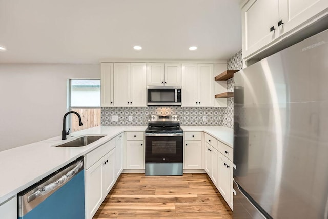 16825 Hamilton Point Cir, Manor, TX 78653 - kitchen featuring stainless steel appliances, open shelves, light wood-style flooring, white cabinetry, and recessed lighting
