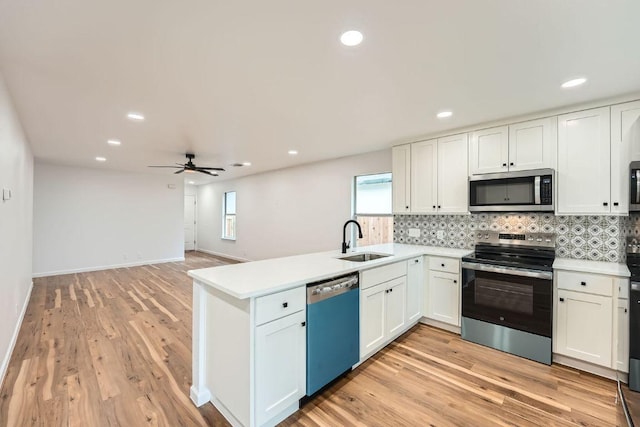 16825 Hamilton Point Cir, Manor, TX 78653 - kitchen with appliances with stainless steel finishes, a peninsula, backsplash, light wood finished floors, and white cabinetry