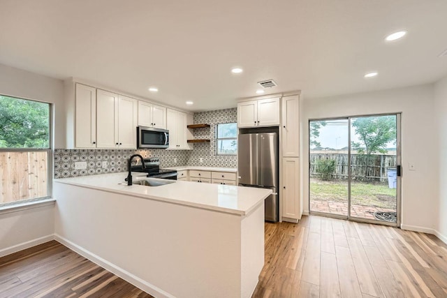 16825 Hamilton Point Cir, Manor, TX 78653 - kitchen featuring appliances with stainless steel finishes, light wood finished floors, light countertops, open shelves, and recessed lighting