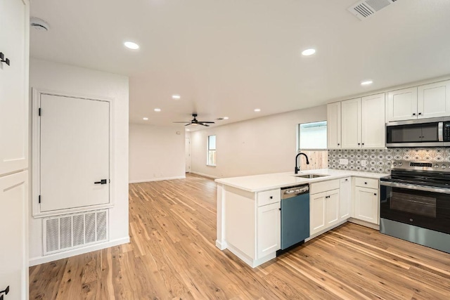 16825 Hamilton Point Cir, Manor, TX 78653 - kitchen with stainless steel appliances, white cabinetry, decorative backsplash, a peninsula, and light wood-type flooring