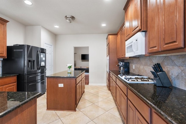 11404 Terrace Meadow Way, Manor, TX 78653 - kitchen with white appliances, a kitchen island, tasteful backsplash, brown cabinets, and dark stone countertops