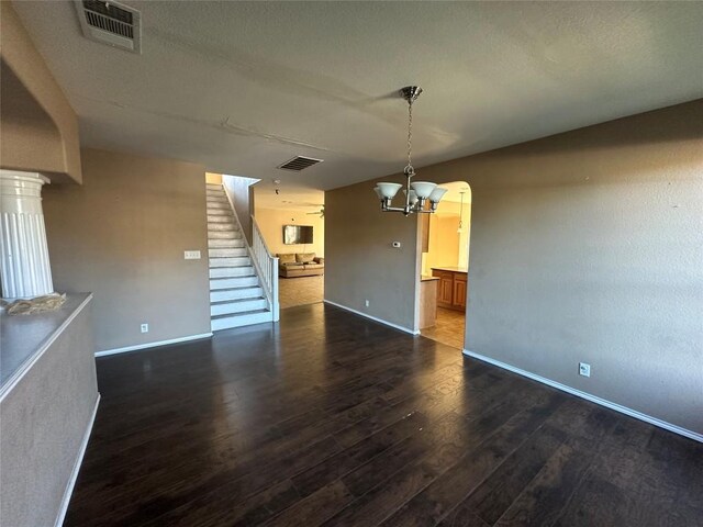 769 Apricot Dr, Kyle, TX 78640 - unfurnished living room with dark wood-style flooring, stairway, a chandelier, and arched walkways