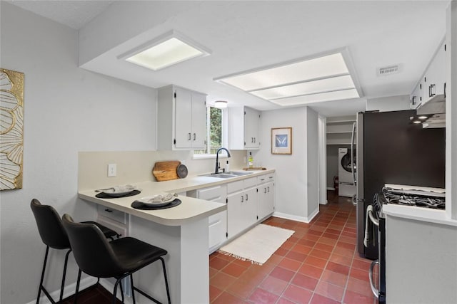 5317 Harvest Ln, Austin, TX 78745 - kitchen featuring stainless steel gas range oven, a peninsula, under cabinet range hood, washer / dryer, and light countertops
