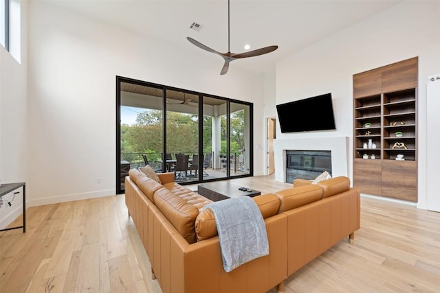 4103 Ridgelea Dr, Austin, TX 78731 - living room with light wood-style flooring, a glass covered fireplace, a ceiling fan, recessed lighting, and a high ceiling