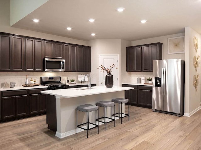 1728 S Main St, Kyle, TX 78640 - kitchen featuring stainless steel appliances, a sink, backsplash, dark brown cabinets, and a breakfast bar area