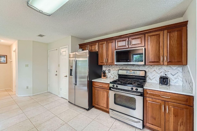 12711 Possum Hollow Dr, Austin, TX 78729 - kitchen featuring appliances with stainless steel finishes, light countertops, brown cabinetry, tasteful backsplash, and light tile patterned floors