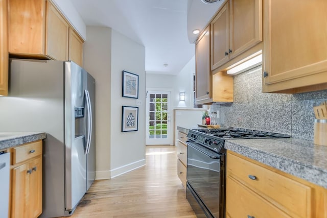 2702 Bonnie Rd, Austin, TX 78703 - kitchen featuring black gas stove, stainless steel fridge, light wood finished floors, decorative backsplash, and light countertops