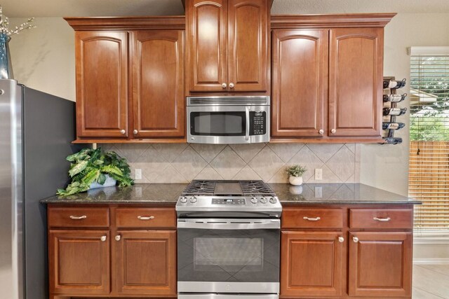 1802 Tall Chief, Leander, TX 78641 - kitchen with appliances with stainless steel finishes, dark stone counters, backsplash, and brown cabinetry