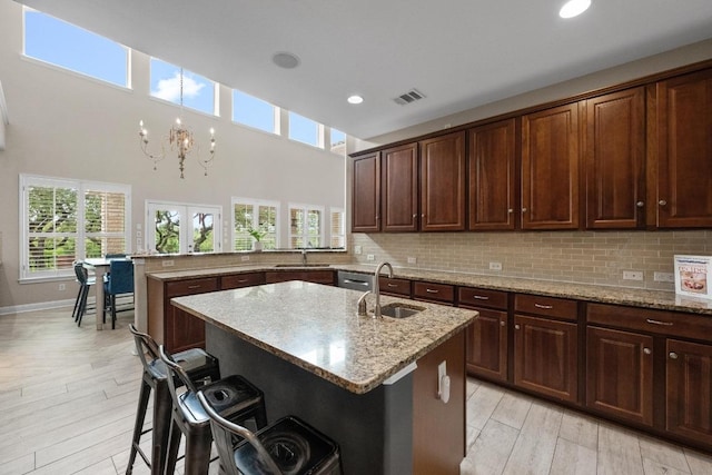 4605 Bat Falcon Dr, Austin, TX 78738 - kitchen with a peninsula, light stone counters, a kitchen bar, tasteful backsplash, and recessed lighting