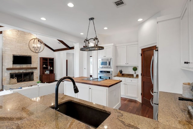 2705 Pyramid Dr, Austin, TX 78734 - kitchen featuring appliances with stainless steel finishes, lofted ceiling, light stone counters, dark wood-type flooring, and white cabinetry