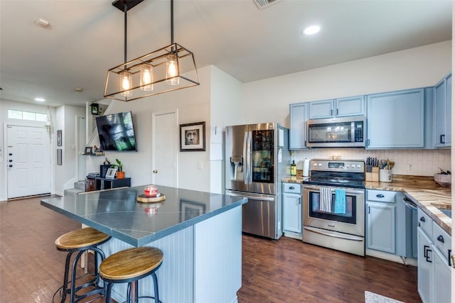 18701 Golden Eagle Way, Elgin, TX 78621 - kitchen featuring stainless steel appliances, blue cabinets, a breakfast bar area, dark wood finished floors, and recessed lighting