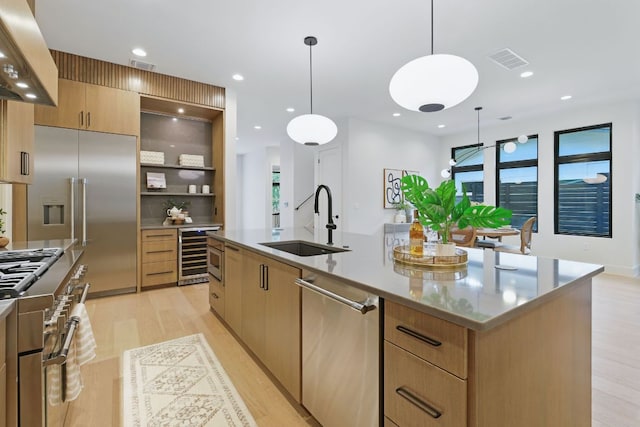 2711 Pegram, Austin, TX 78757 - kitchen featuring wine cooler, premium appliances, extractor fan, light wood-style flooring, and an island with sink