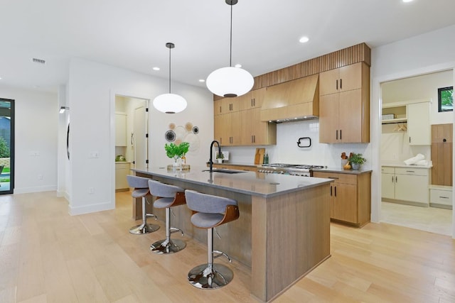 2711 Pegram, Austin, TX 78757 - kitchen featuring custom exhaust hood, light wood-type flooring, recessed lighting, a kitchen bar, and a kitchen island with sink