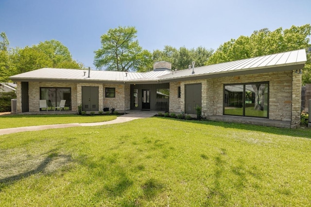 2401 Manana St, Austin, TX 78730 - back of house featuring a standing seam roof, a chimney, a yard, and stone siding