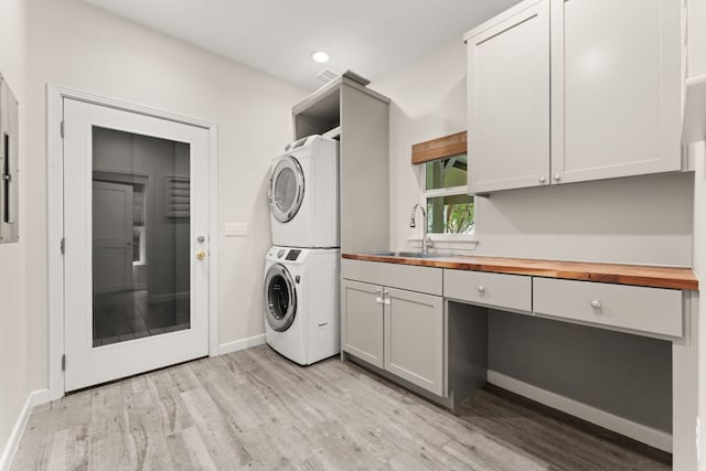 5212 Valley Oak Dr, Austin, TX 78731 - laundry area with estacked washer and dryer, cabinet space, light wood-style flooring, and recessed lighting