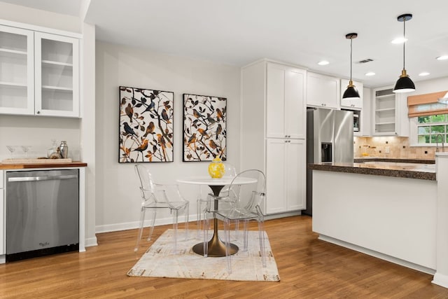 5212 Valley Oak Dr, Austin, TX 78731 - kitchen with stainless steel appliances, white cabinetry, light wood finished floors, glass insert cabinets, and tasteful backsplash