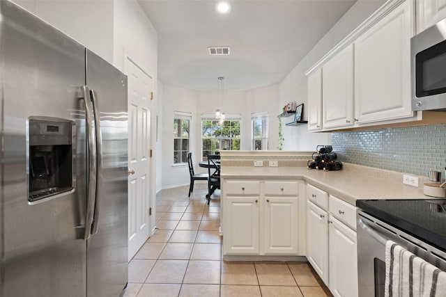 9204 Brents Elm Dr, Austin, TX 78744 - kitchen featuring appliances with stainless steel finishes, light tile patterned floors, white cabinetry, tasteful backsplash, and a peninsula