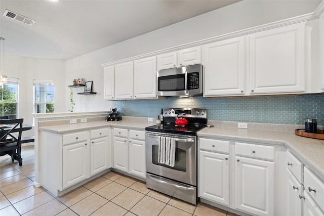 9204 Brents Elm Dr, Austin, TX 78744 - kitchen featuring stainless steel appliances, a peninsula, white cabinets, light tile patterned floors, and decorative backsplash