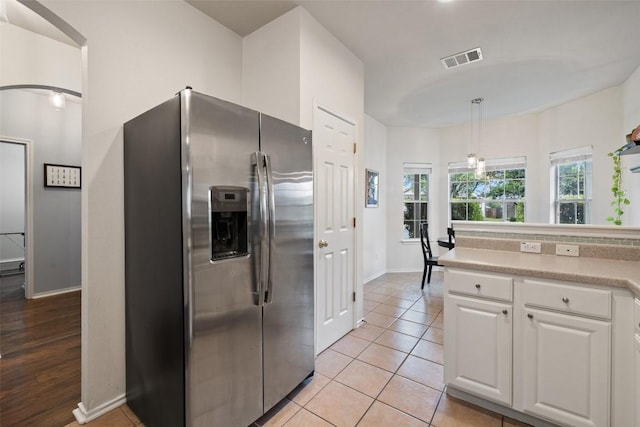 9204 Brents Elm Dr, Austin, TX 78744 - kitchen featuring stainless steel refrigerator with ice dispenser, white cabinetry, light countertops, decorative light fixtures, and light tile patterned flooring