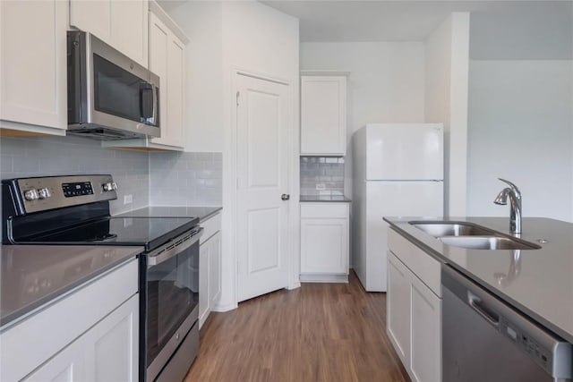 421 Bluejack Way, Hutto, TX 78634 - kitchen featuring appliances with stainless steel finishes, wood finished floors, white cabinets, backsplash, and dark countertops