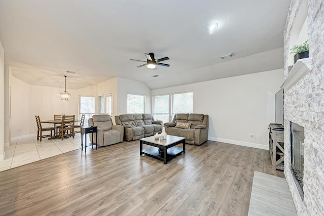 500 Olympic Dr, Pflugerville, TX 78660 - living area featuring a ceiling fan, a stone fireplace, light wood-style floors, lofted ceiling, and a chandelier