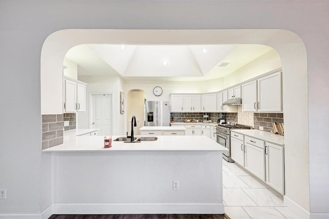 500 Olympic Dr, Pflugerville, TX 78660 - kitchen featuring appliances with stainless steel finishes, under cabinet range hood, arched walkways, and backsplash