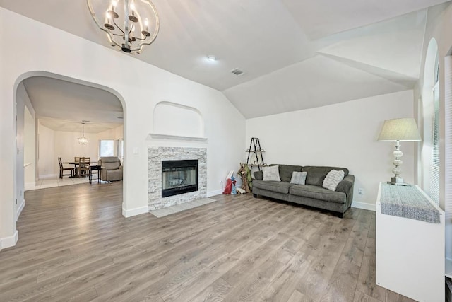 500 Olympic Dr, Pflugerville, TX 78660 - living room with arched walkways, a chandelier, light wood-style floors, vaulted ceiling, and a fireplace with flush hearth