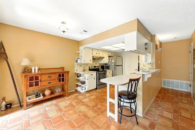 2500 Dana Cv, Austin, TX 78746 - kitchen with stainless steel appliances, open shelves, under cabinet range hood, light countertops, and a breakfast bar area