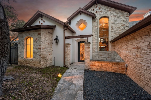 8140 Joy Rd, Volente, TX 78641 - exterior entry at dusk with stone siding and stucco siding