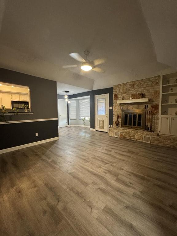 607 Garden Path Cv, Round Rock, TX 78664 - unfurnished living room with wood finished floors, ceiling fan, a fireplace, and built in shelves