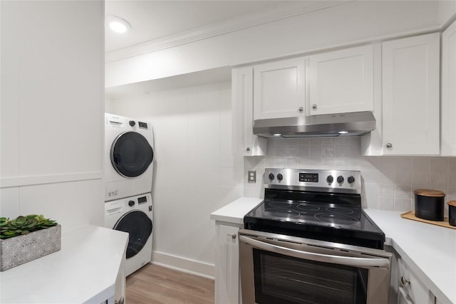 2122 Hancock Dr Unit 103, Austin, TX 78756 - kitchen with stainless steel electric stove, under cabinet range hood, stacked washer / dryer, light countertops, and crown molding