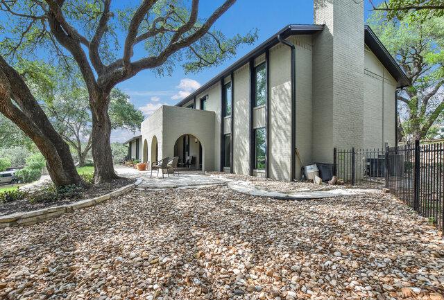 6203 Olympic Overlook Dr, Austin, TX 78746 - back of house with a chimney, a patio, stucco siding, and brick siding