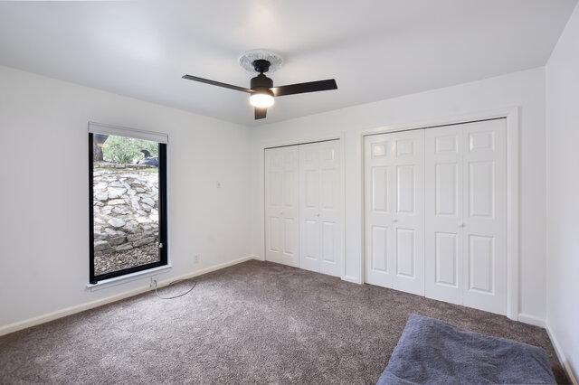 6203 Olympic Overlook Dr, Austin, TX 78746 - unfurnished bedroom with carpet floors, two closets, and ceiling fan