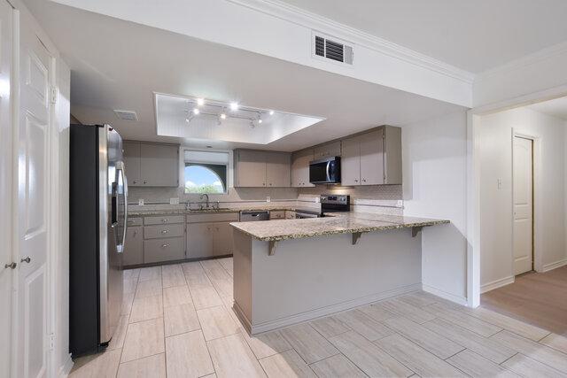 6203 Olympic Overlook Dr, Austin, TX 78746 - kitchen featuring stainless steel appliances, gray cabinetry, a peninsula, a tray ceiling, and tasteful backsplash