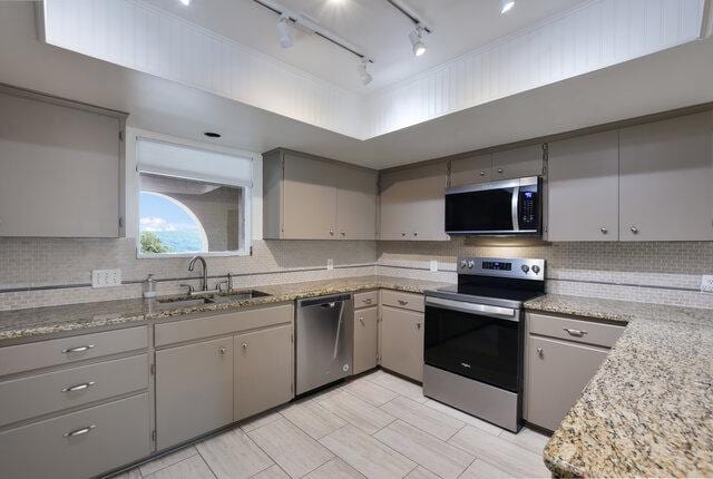6203 Olympic Overlook Dr, Austin, TX 78746 - kitchen featuring appliances with stainless steel finishes, gray cabinets, tasteful backsplash, and rail lighting