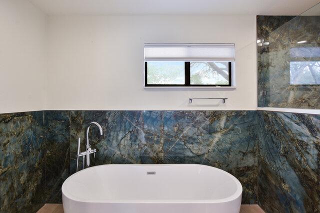 6203 Olympic Overlook Dr, Austin, TX 78746 - bathroom featuring a freestanding tub and tile walls