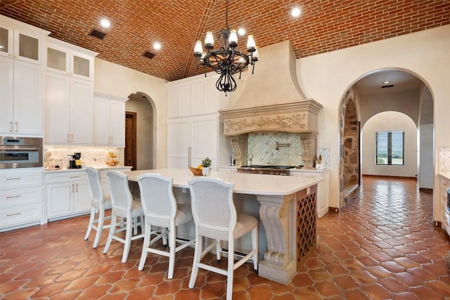 108 Country Vista Ln, Georgetown, TX 78626 - kitchen featuring high vaulted ceiling, stainless steel oven, arched walkways, a kitchen island with sink, and decorative backsplash