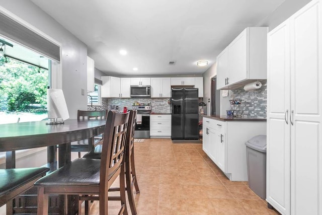 1102 Girard St, San Marcos, TX 78666 - kitchen featuring stainless steel appliances, tasteful backsplash, dark countertops, light tile patterned floors, and recessed lighting