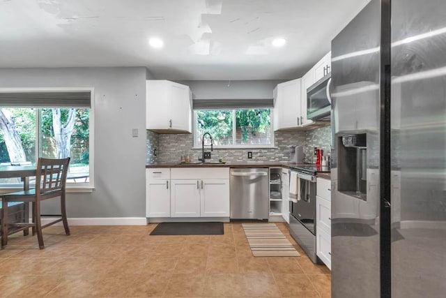 1102 Girard St, San Marcos, TX 78666 - kitchen with stainless steel appliances, decorative backsplash, dark countertops, white cabinets, and recessed lighting