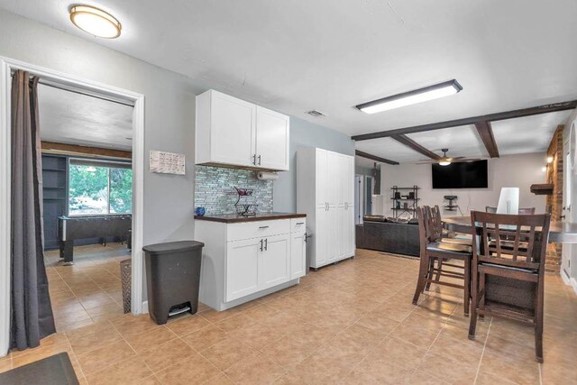 1102 Girard St, San Marcos, TX 78666 - kitchen featuring ceiling fan, light tile patterned flooring, white cabinets, and beamed ceiling