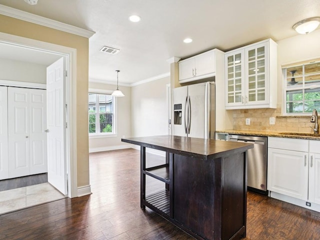 3811 Byron Dr, Austin, TX 78704 - kitchen with stainless steel appliances, crown molding, white cabinets, glass insert cabinets, and dark wood-style floors