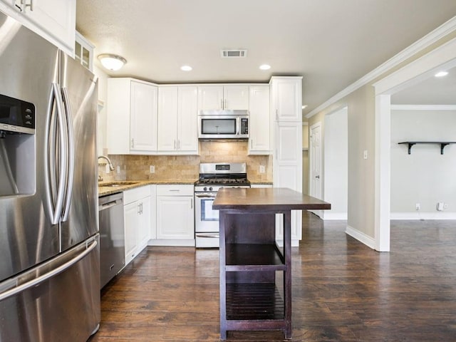 3811 Byron Dr, Austin, TX 78704 - kitchen with stainless steel appliances, light stone counters, backsplash, white cabinetry, and ornamental molding