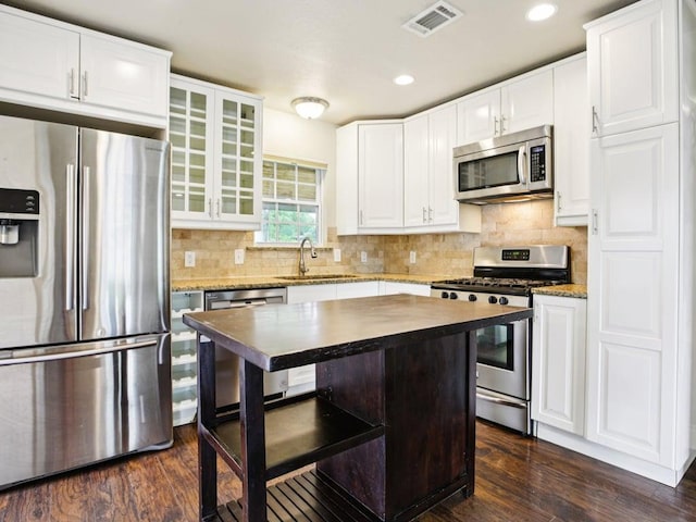 3811 Byron Dr, Austin, TX 78704 - kitchen featuring appliances with stainless steel finishes, dark wood-style floors, glass insert cabinets, white cabinets, and recessed lighting