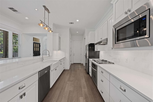 1403 W 12th St Unit B, Austin, TX 78703 - kitchen with appliances with stainless steel finishes, under cabinet range hood, white cabinetry, dark wood-style floors, and recessed lighting